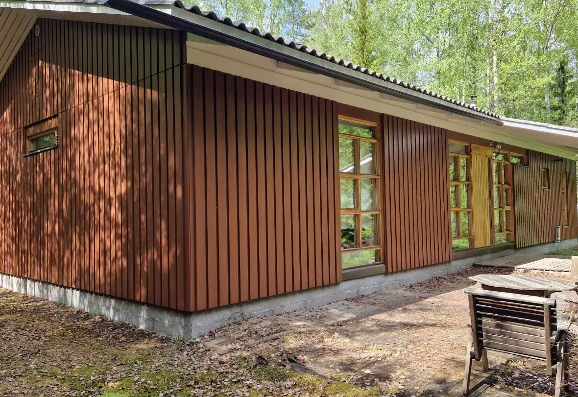 Punaruskeaksi maalattu puinen piharakennus metsän reunassa